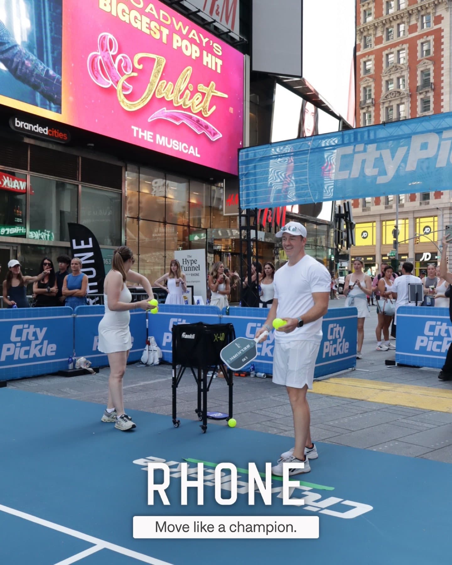 Guests playing pickleball on the branded City Pickle court in Times Square, framed by Rhone's inflatable "Hype Tunnel" entrance.