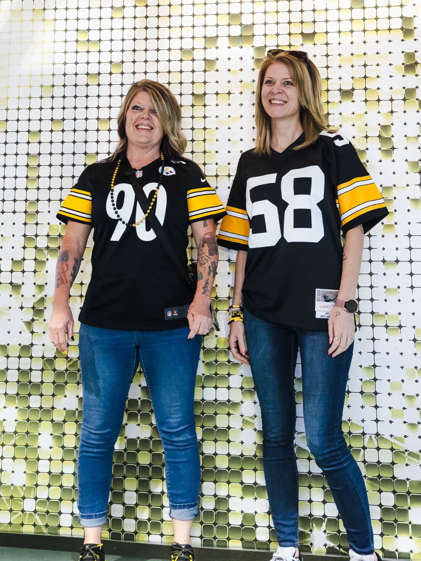 Two fans in Steelers jerseys posing at the shimmer-wall capture station.