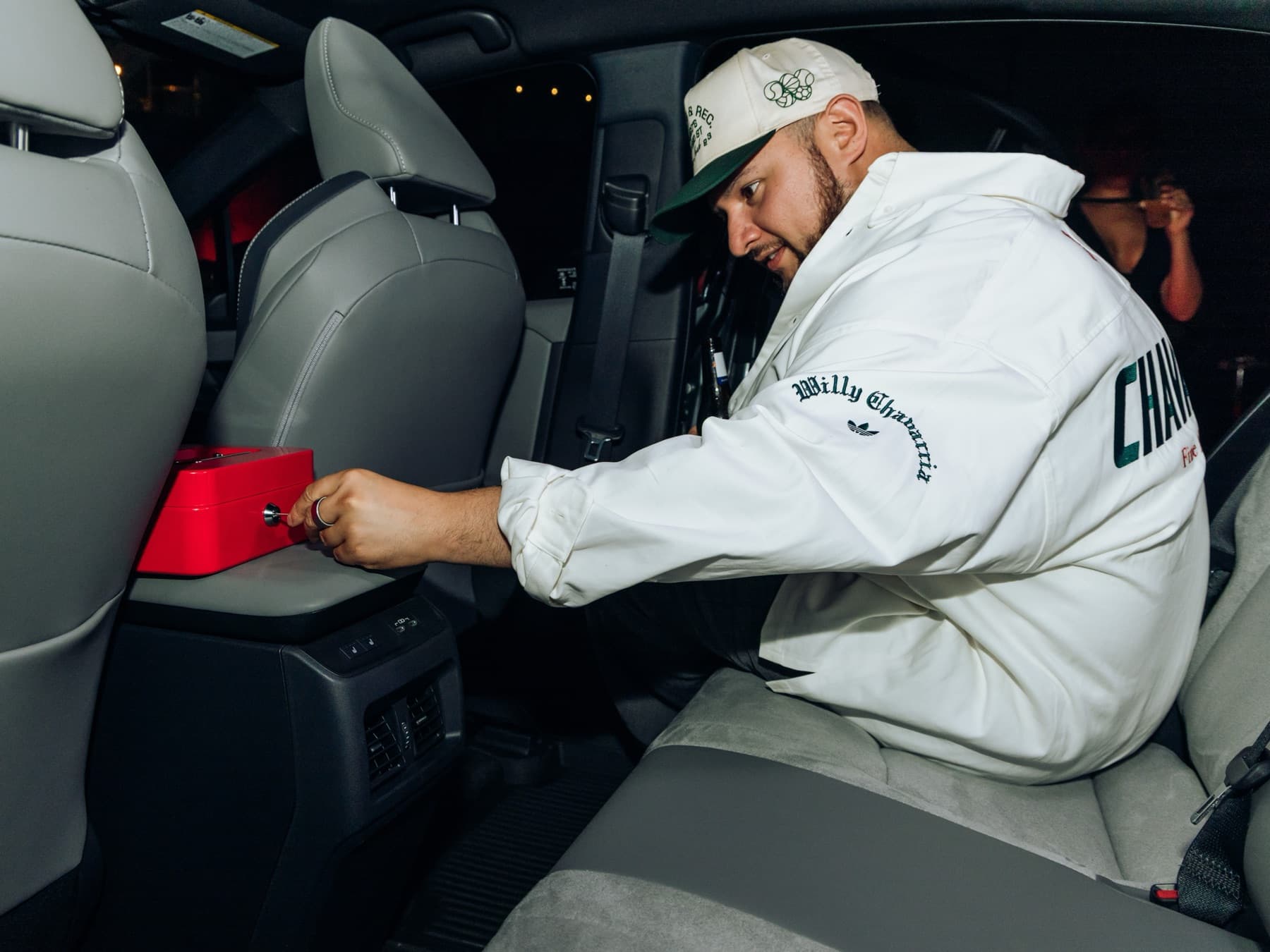 A guest seated in the back of the Toyota C-HR mid-capture, lit in red under the venue's NYFW party lighting.