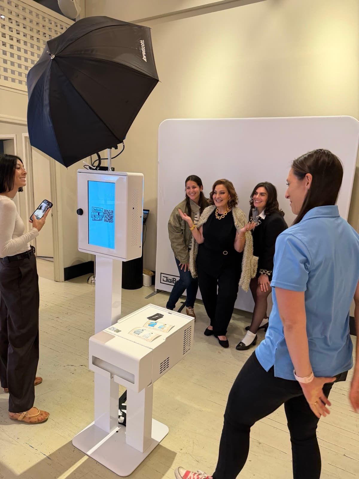 Guests using an open-air selfie booth with studio lighting at a corporate reception.