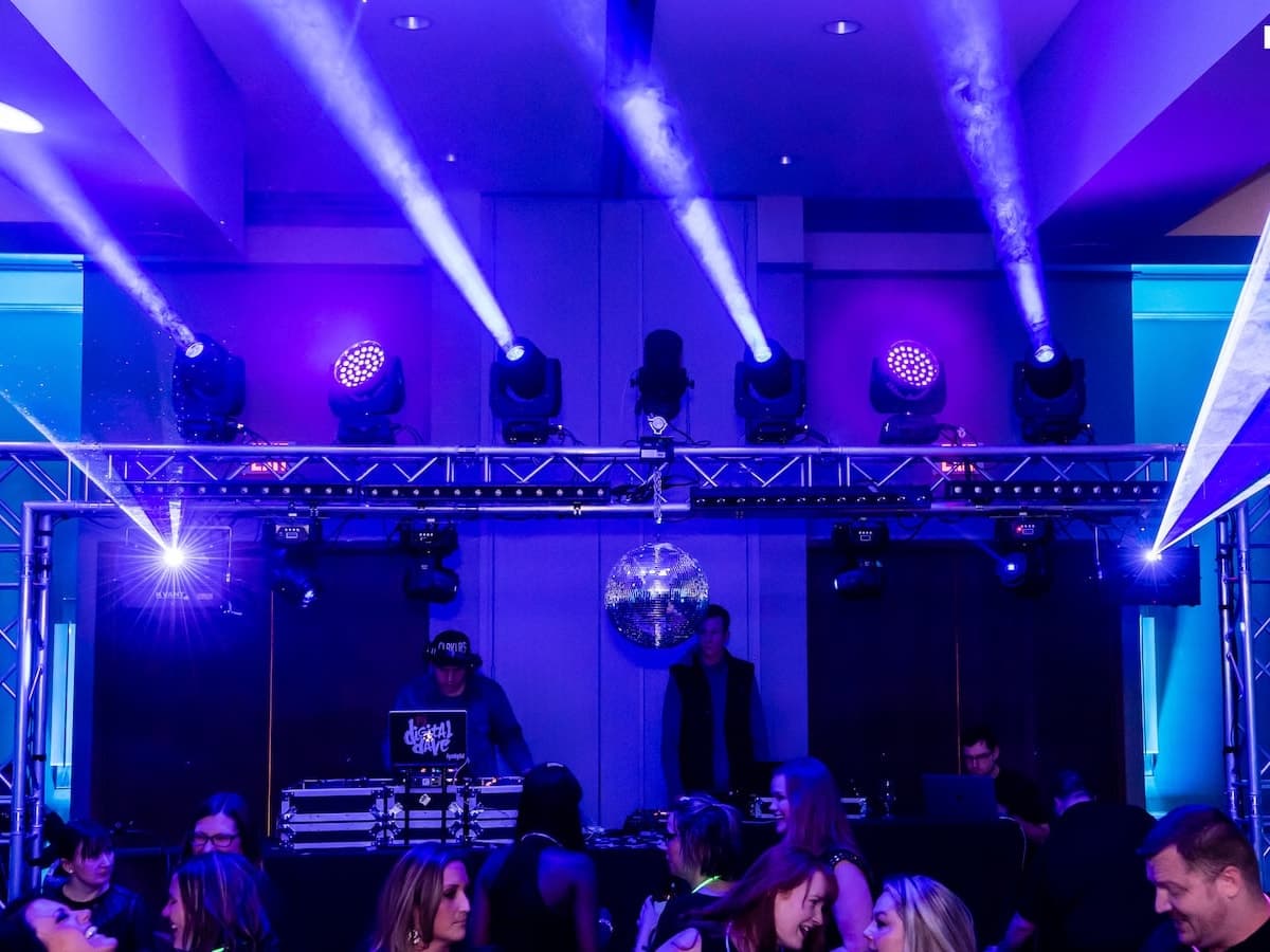 DJ booth under a truss of blue moving-head fixtures at a corporate ballroom event.