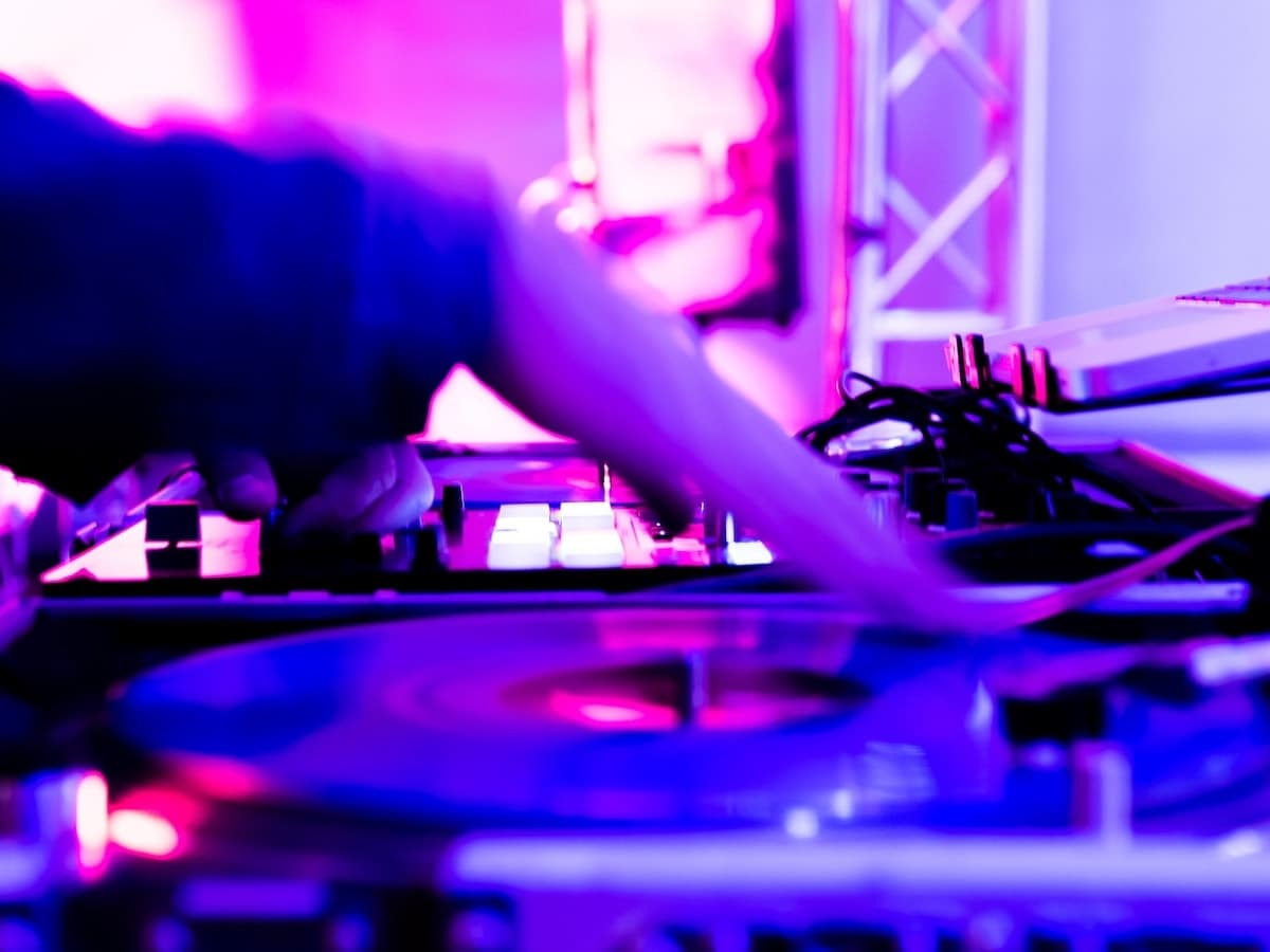 DJ's hands mixing on turntables under purple stage lighting at a corporate event.