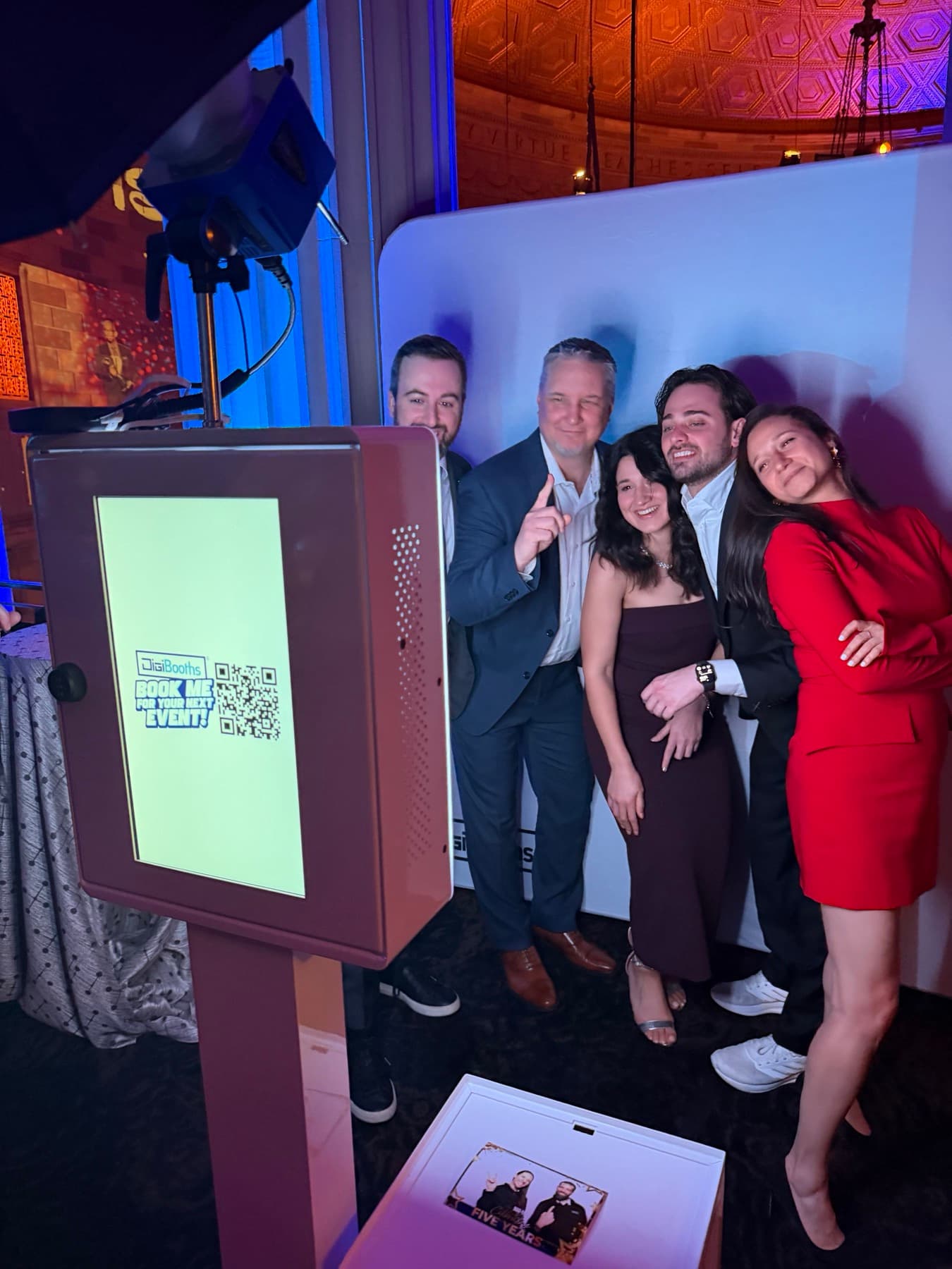 Guests reviewing and sharing photos at a booth kiosk during a gala reception.